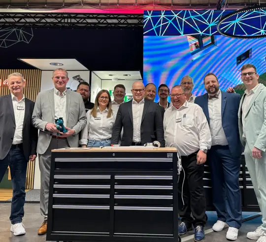 Eine Gruppe von Mitarbeitern steht an einem Messestand