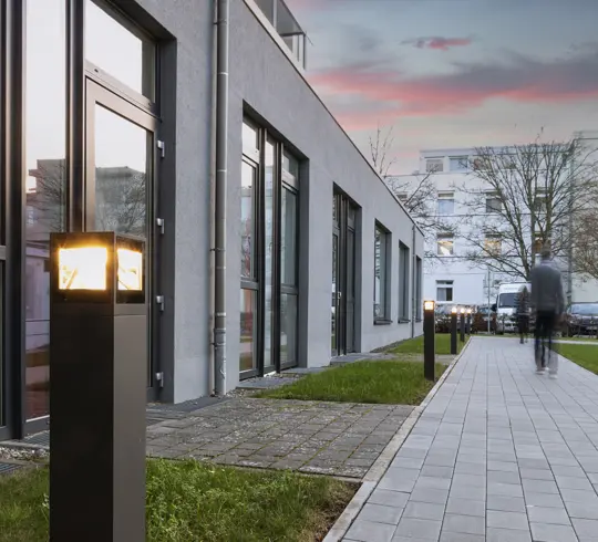 A hospital garden at dusk, with the path lights switched on