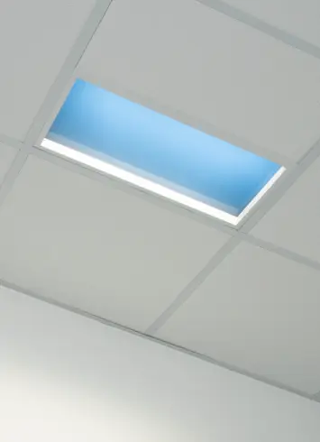 Moderne Deckenbeleuchtung mit bläulichem Licht, das an Tageslicht erinnert, in rechteckigen Panels integriert.