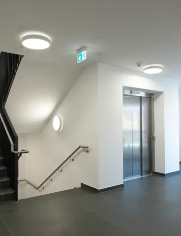 A modern stairwell with several round light fittings and a lift