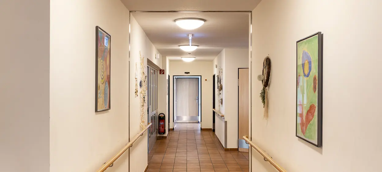Ein beleuchteter Flur mit QUICK-FIX plus Deckenleuchten, Wanddekorationen und Holzhandläufen.