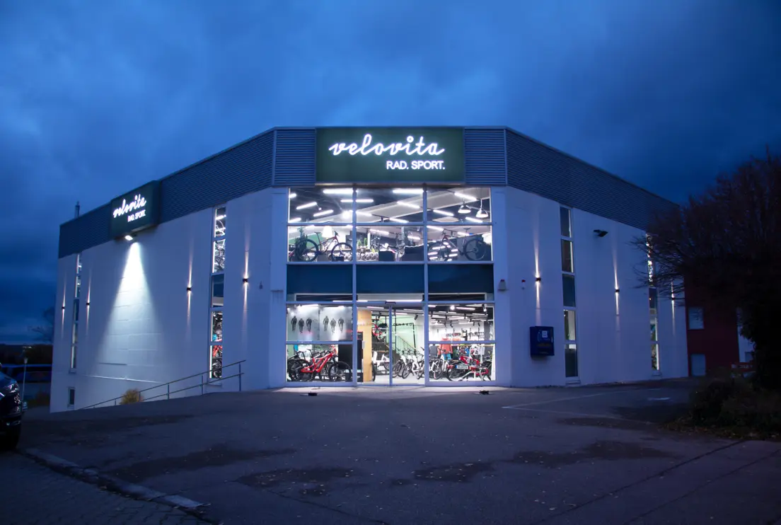 The Velovita bike shop at dusk, with its outdoor lighting switched on