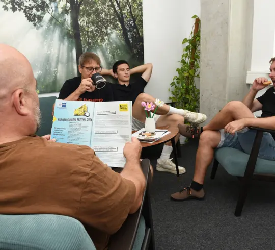 Eine Gruppe von 5 Männern, die entspannt um einen Tisch herumsitzen