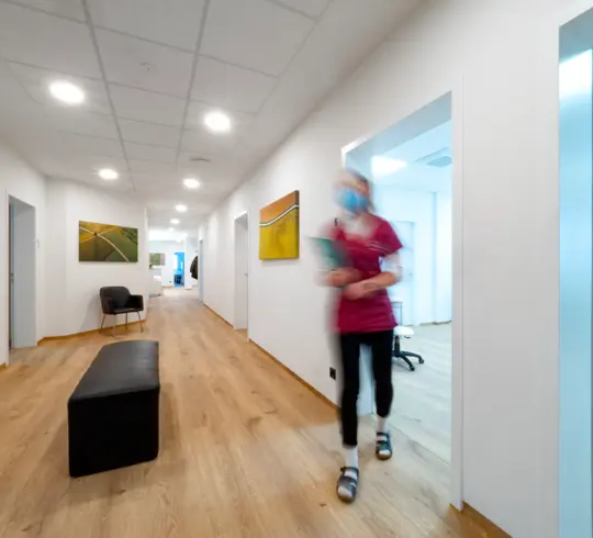 The reception area of a doctor’s surgery, into which a medical assistant is just walking