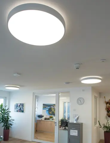 The common room of a care home with large, round lights on the ceiling