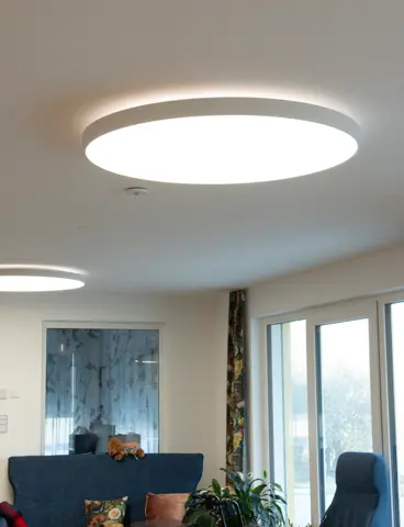 The common room of a care home with large, round lights on the ceiling