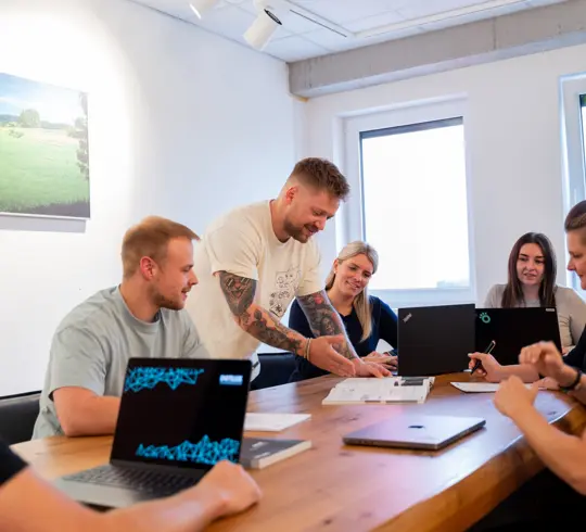 Eine Gruppe von Mitarbeitern bei einem Meeting, sitzend an einem Schreibtisch