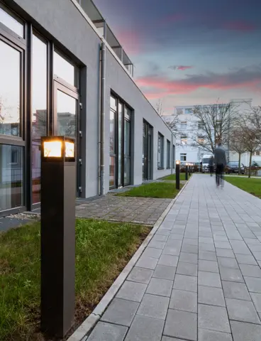 A hospital garden at dusk, with the path lights switched on
