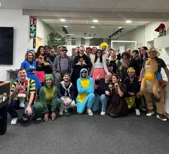 Eine große Gruppe verkleideter Menschen die im DOTLUX Büro Fasching in Kostümen feiern