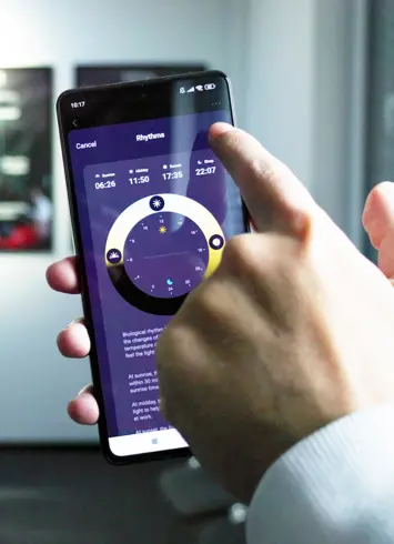 Person bedient Smartphone mit einer App zur Steuerung biologischer Rhythmen, einschließlich Sonnenaufgang, Sonnenuntergang und Schlafenszeit.