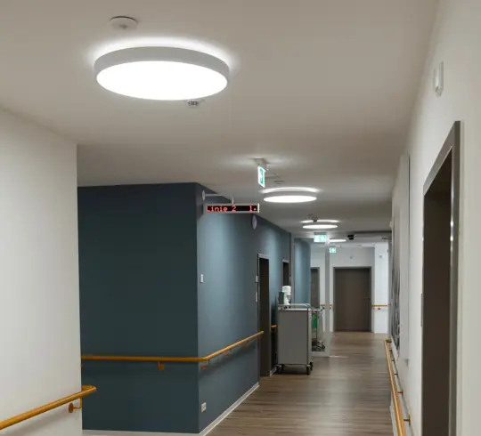 The corridor of a care home with large, round ceiling lights