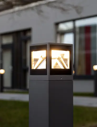 An outdoor light made of metal and glass, with one side hinged open