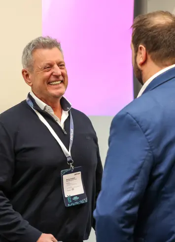 A cheerful group of six at an outdoor event, with drinks and balloons in the background.