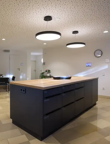 A dark kitchen unit, above which two round pendant lights hang and shine