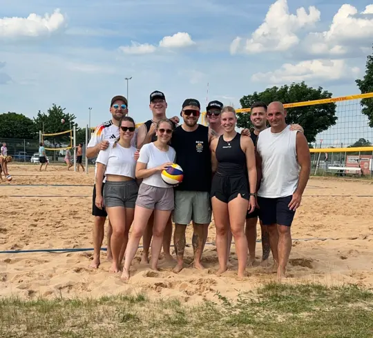 Eine Gruppe von Menschen steht zusammen auf einem Beachvolleyballfeld des TSV Weißenburg