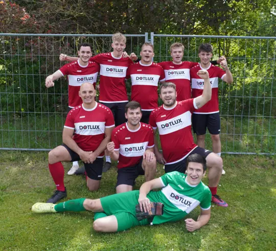 Eine Gruppe von Menschen in Fußballtrikots auf einer Wiese, die sich über ihre Leistung bei der Weißenburger Stadtmeisterschaft der Betriebe freuen