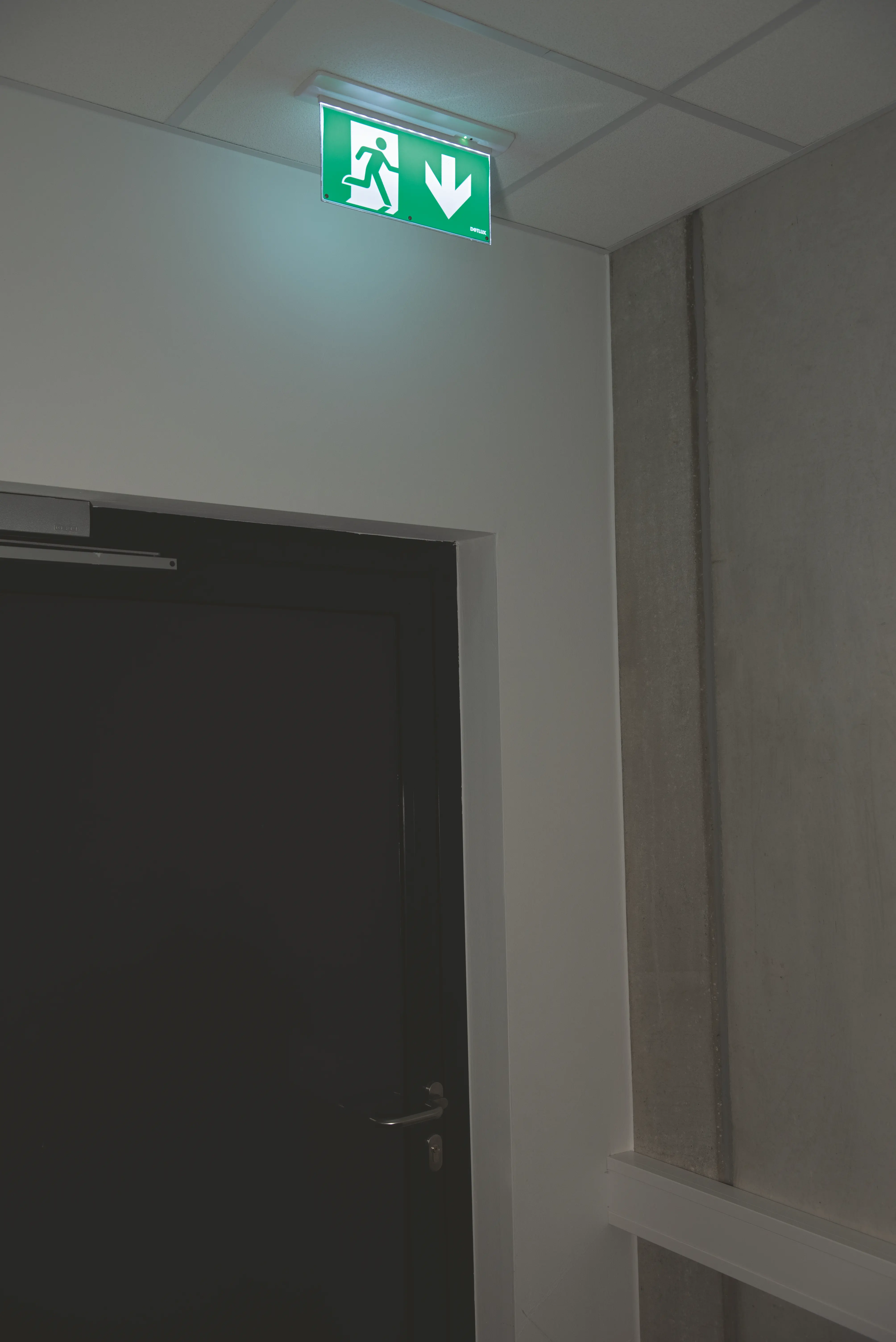 A glowing emergency light on the ceiling indicating an escape route