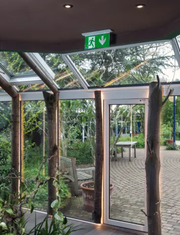 Eine Glasfassade mit einer Notleuchte, die davor innen an der Decke hängt