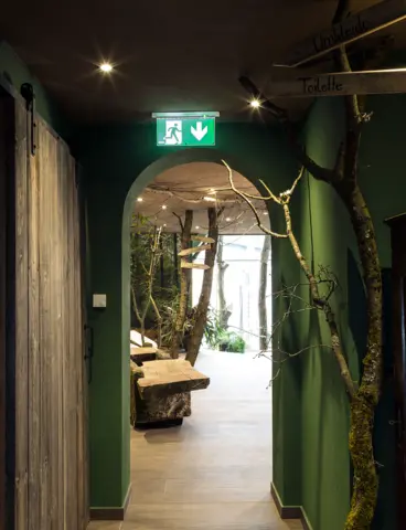 Ein grüner, bewachsener Durchgang in einem Hotel mit einer Notleuchte an der Decke