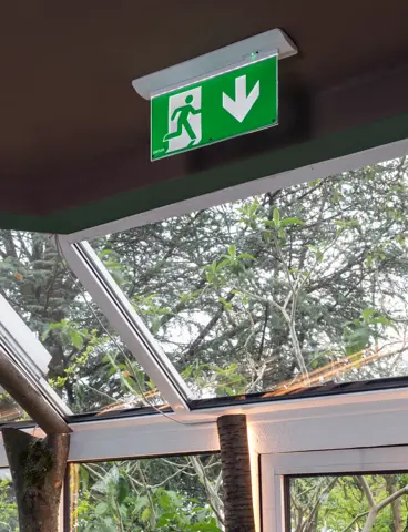 Eine Glasfassade mit einer Notleuchte, die davor innen an der Decke hängt