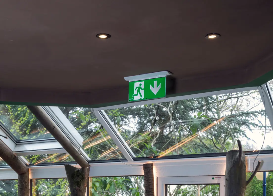 Eine Glasfassade mit einer Notleuchte, die davor innen an der Decke hängt